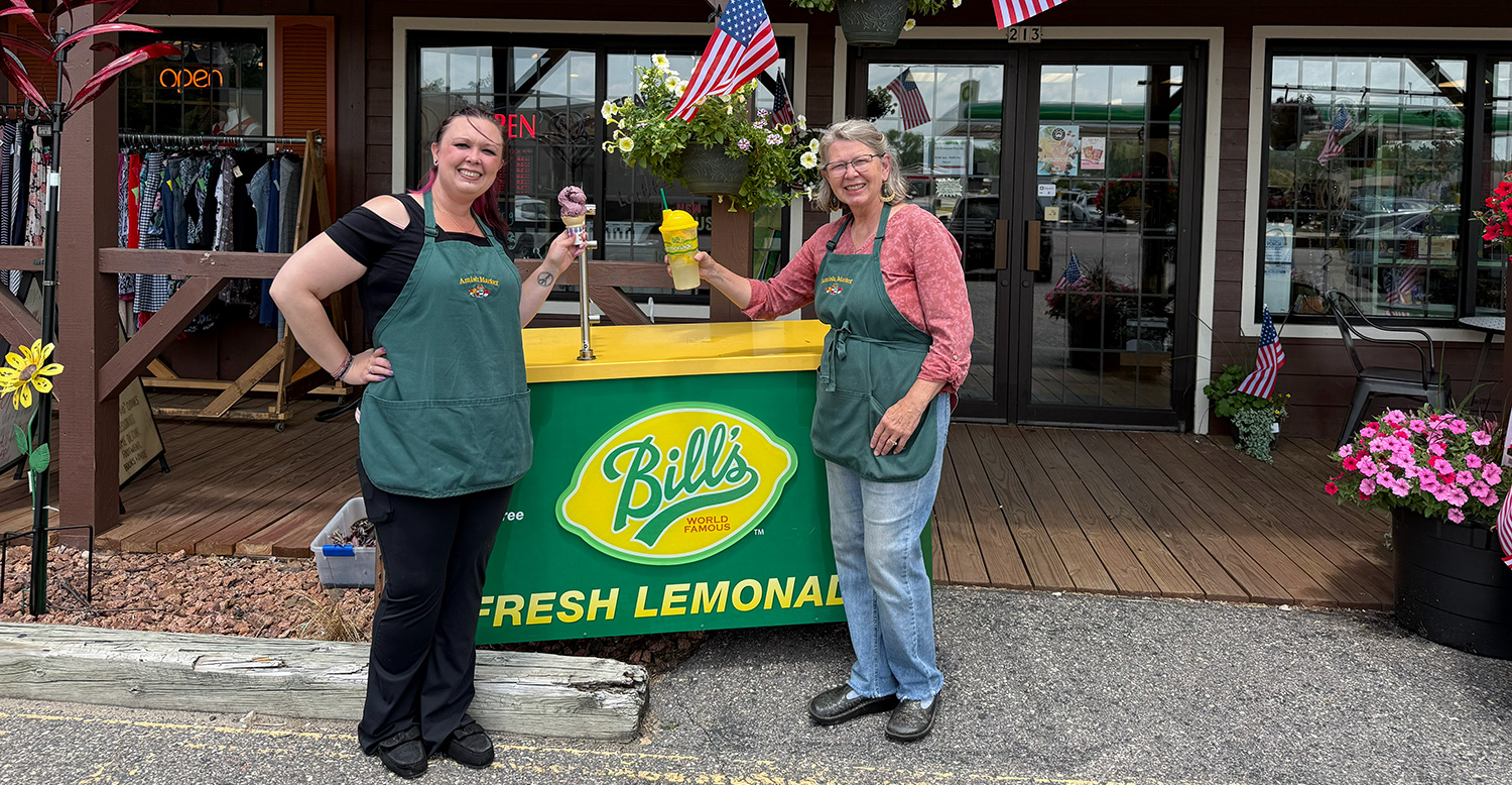 Amish House Market employees with ice cream and lemonade treats, outside in from of a cart showing Bill's Famous Fresh Lemonade sign